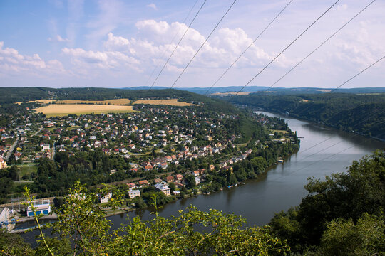 Panoramic view of Vran&eacute; nad Vltavou and the Vltava River amidst forested hills and summer countryside.