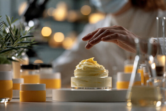 Hand reaching for a jar of cream in a laboratory filled with various skincare products during a research session