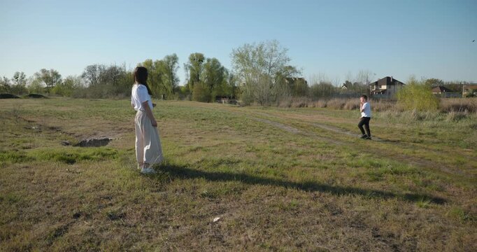 Mother with Children Throw Flying Disk Playing Outside. Family spend time together on nature. 4K 10-bit