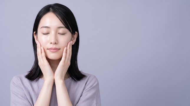Young Japanese woman cupping her face in a cozy well lit interior, dermatology and healthy skin concept, ideal for skincare brand advertising