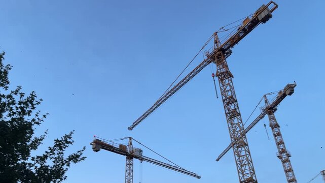 Three big cranes with a background of a blue sky. Construction industry job, working in construction, building process
