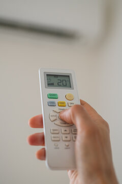 Air conditioner remote control displaying 20&deg;C while changing cooling settings. Smart home climate control, temperature regulation and indoor air conditioning in a modern interior.