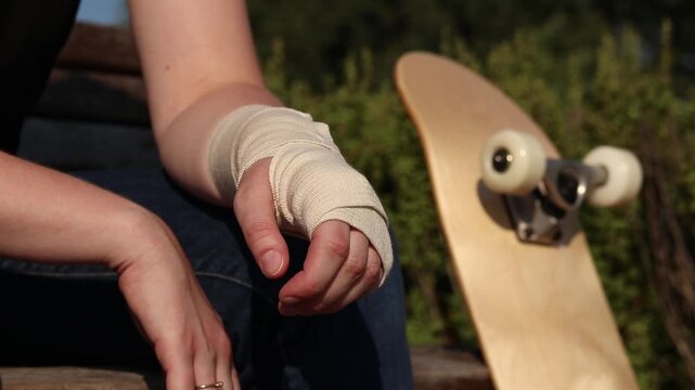 Unsuccessful fall from skateboard and hand injury. Injured hand in medical bandage next to skateboard close-up. Shot highlights risks of street sports, training failures and rehabilitation process