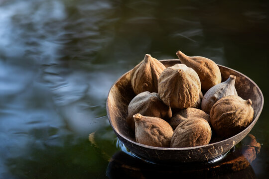  Terminalia bellirica or Beleric Myrobalan fruits placed on floating vessel against natural backdrop.