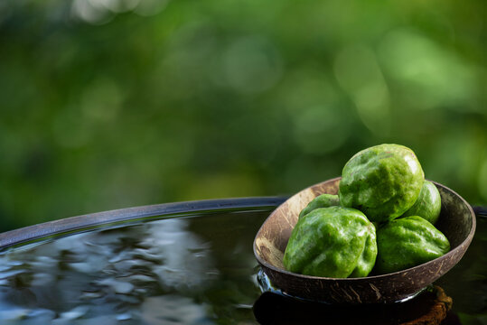 Terminalia chebula or Chebulic Myrobalans fruits placed on floating vessel against natural backdrop.