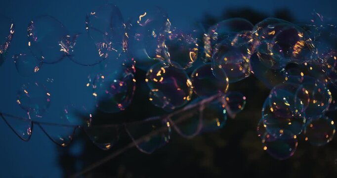 Close up view of giant soap bubbles floating during an evening street performance in a public space.