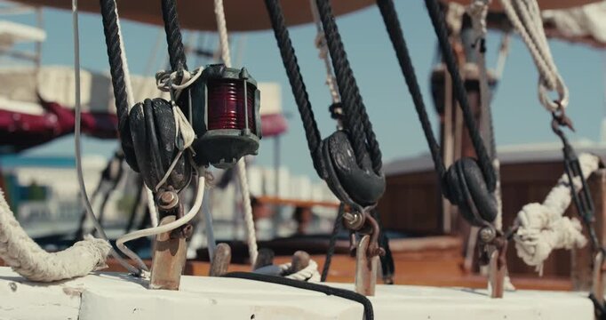 Rigging, pulleys, ropes, and a navigation light are visible on the deck of a historic wooden sailing ship.