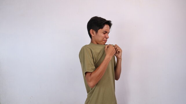 Asian young man gesturing to smell his body odor which smells bad