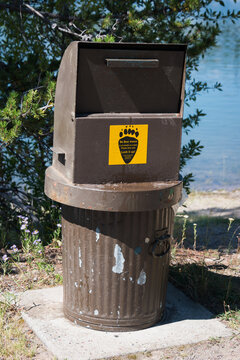 bear proof metal waste bin in national park with yellow paw footprint sticker