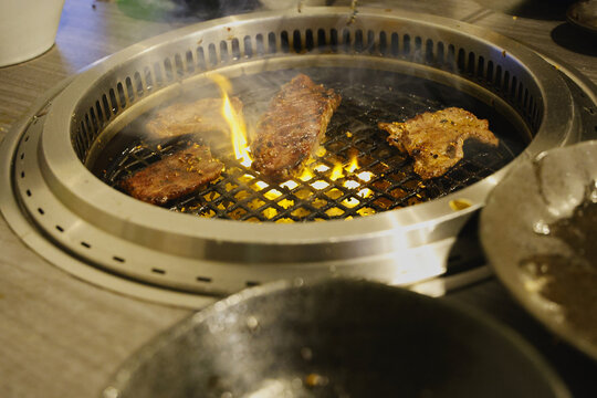 焼肉屋で厚切りのリブロースステーキを焼いているシーン