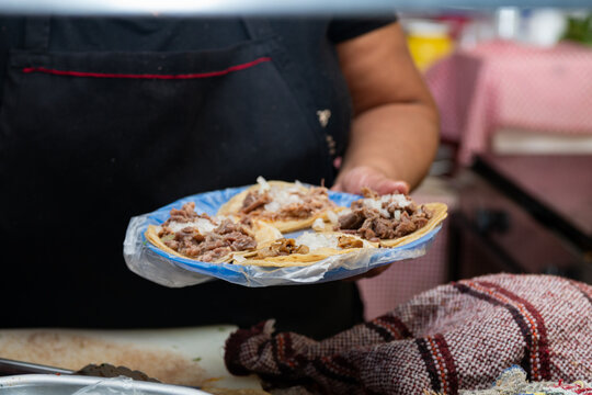 Close-up of hands preparing fresh street tacos with meat, onion and cilantro