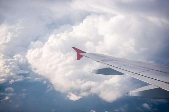 Airplane wing over bright clouds seen from window seat
