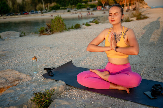 Woman practicing yoga meditation on beach by the sea