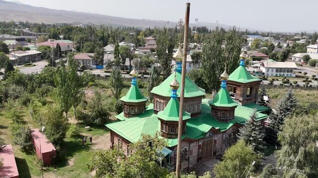 Karakol, Kyrgyzstan &ndash; October 4, 2025: Wooden Orthodox church with green domes and ornate carvings, a city landmark.