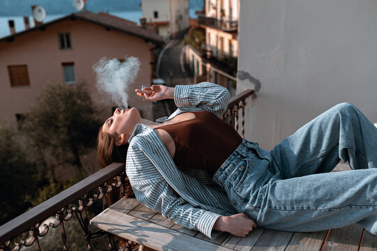 Young woman smoking on balcony overlooking Italian street