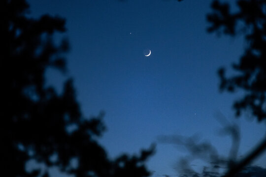 Crescent moon in twilight sky with planet visible