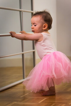 Baby girl learning ballet dancing at a barre