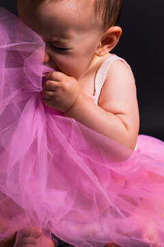 Baby girl hiding face in pink tutu fabric