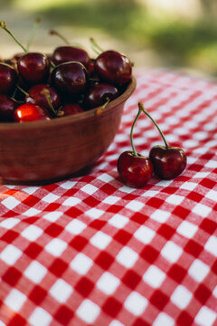 Ripe cherries in a bowl on a red checkered cloth