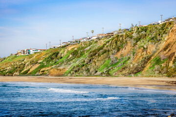 Oceanfront homes perched on a lush green cliff overlooking the Pacific Ocean © EJ