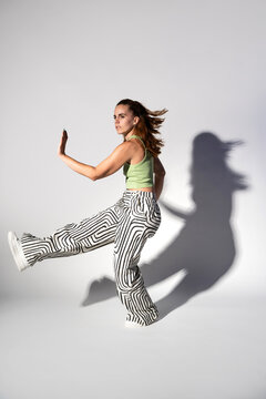 Urban woman dancer in striped pants with dramatic shadow