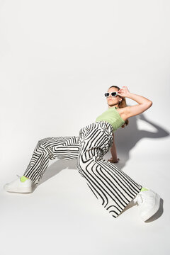 Urban woman dancer in striped pants and white sunglasses