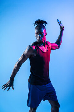 African male dancer pose under neon studio lighting