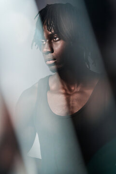 African man portrait through reflective glass in shadow