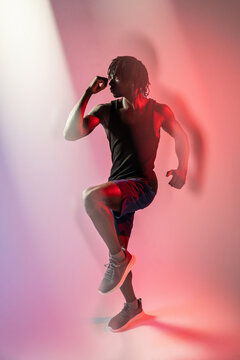 African man perform high knee exercise in red light