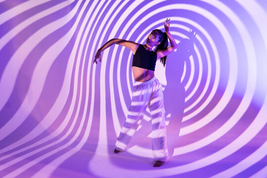 Latin woman dancer posing in purple abstract light projection