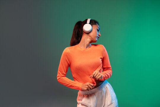 Latin woman dance with headphones against colorful background