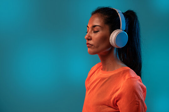 Latin woman wearing headphones with closed eyes and copy space