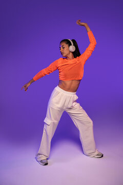 Latin woman dance with headphones in purple studio