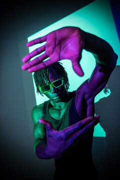 African man posing with neon light and frame gesture