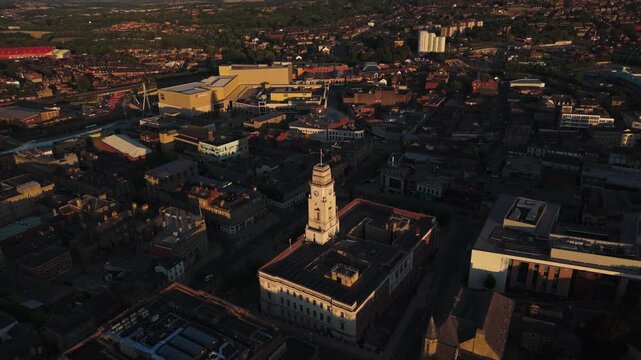 Aerial fly forward and rising shot toward Barnsley Town Hall and cityscape, UK.