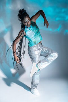 Afro woman dancer posing in studio with teal light