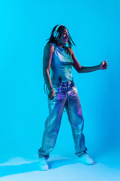 Afro woman dancer enjoying music in neon blue studio