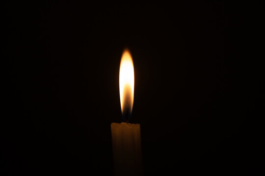 Burning candle flame isolated against pure pitch black background