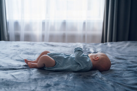Newborn baby lying on bed in soft morning window light