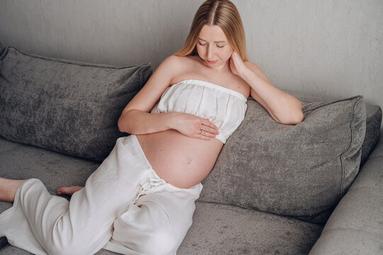 Pregnant woman relaxing on sofa at home, lifestyle