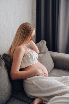 Pregnant woman relaxing on sofa at home in soft light