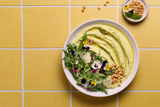 Pesto hummus with arugula and edible flowers