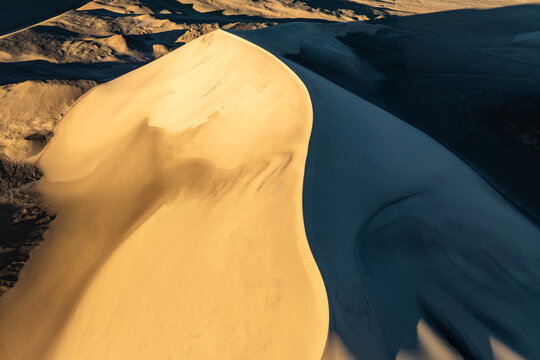 Wind-sculpted sand dune patterns with dramatic light
