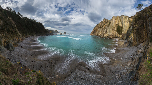 Asturian rocky cove with turquoise sea under cloudy sky
