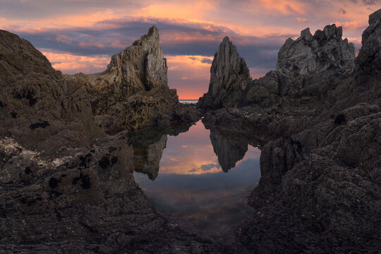 Rugged Asturian sea stacks and sunset reflection tide pool