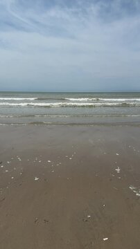 Waves rolling onto sandy beach in Berck sur mer under cloudy sky