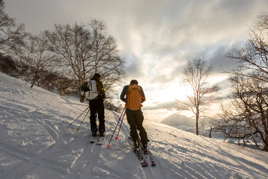 Two men splitboarding at sunset with Mount Yotei in Hokkaido, Japan