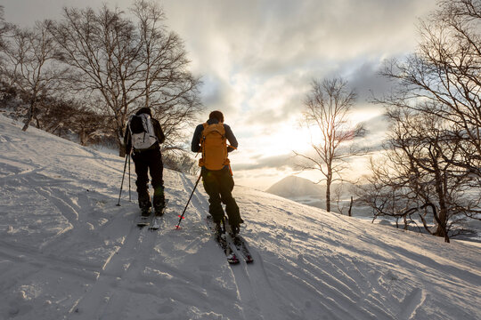 Two men splitboarding at sunset with Mount Yotei in Hokkaido, Japan