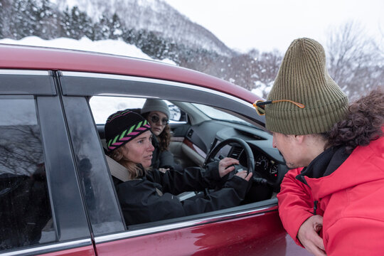 Friends talking by car during a snowy winter day