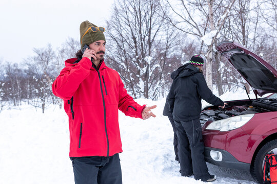 Friends helping with car trouble in snowy winter landscape